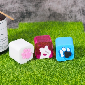 Three cat paw resin molds in pink, blue and white colors on a green lawn backdrop