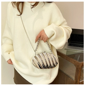 Detail of silver shell-shaped acrylic clutch with metallic beads and chain strap