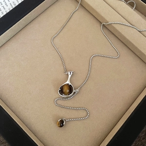 Detailed macro view of the silver necklace with hollow pendant and round tiger eye stone