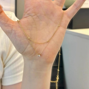 Double layered gold necklace with round beads and a sparkling single zircon pendant