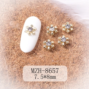 Detailed macro of golden alloy snowflake nail charms with white rhinestones