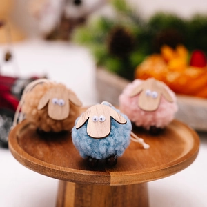 Three handmade wool felt sheep ornaments with wooden legs on a rustic tray