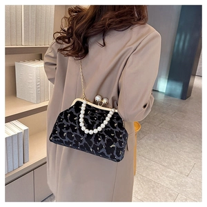 Detail of leopard print velvet shell bag with pearl handle and golden chain on beige blazer