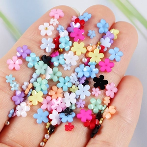 Colorful resin flower nail charms and beads held in hand for DIY manicure craft decoration