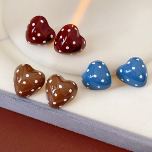 Detailed view of heart-shaped polka dot earrings in red, brown and blue colors