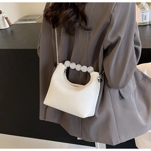 Close-up of white lychee pattern pearl handbag with metal chain and bead handle