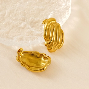 Detail of gold irregular wave textured 18K stainless steel earrings on frosted glass
