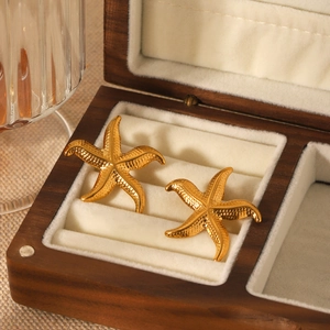 Boucles d'oreilles étoiles de mer dorées en acier inoxydable dans un écrin de bijoux en bois