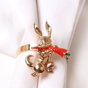 Detail of golden bunny napkin ring with red carrot on white cloth for table decor