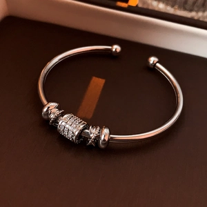 Macro detail of silver zircon inlaid open bangle with polished beads on leather background