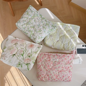 Detailed macro view of four floral quilted cotton makeup bags in soft pastel colors