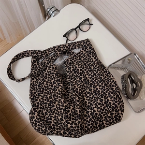 Dettaglio della borsa tote in tela maculata con accessori moda su un tavolo bianco