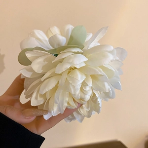 Detail of white handmade fabric lotus hair clip with green leaves in a handheld view