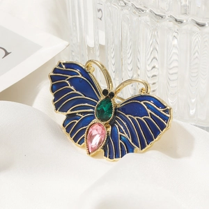 Vue macro d'une broche papillon en émail bleu sertie d'une pierre précieuse vert émeraude