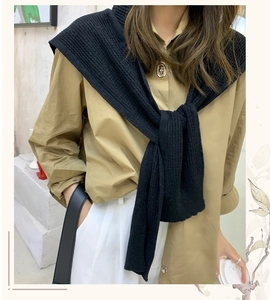 Close-up of a stylish black knitted hooded scarf styled as a shawl over a khaki shirt