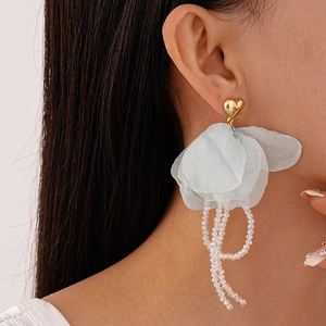 Détail de boucles d'oreilles pétales en dentelle bleue avec franges en cristal