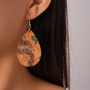 Detail of teardrop cork earrings with bohemian paisley patterns worn by a model