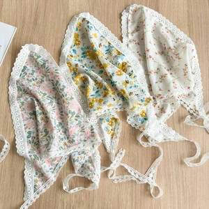 Pañuelos triangulares con estampado floral y encaje en blanco y rosa sobre madera