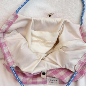 Detailed view of plaid tote interior with beige lining, zipper pocket and snap button