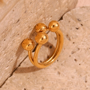Macro shot of 18K gold plated double-band ring with three spheres on stone background
