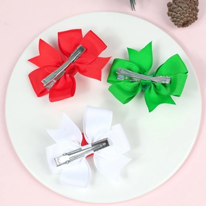 Three Christmas grosgrain ribbon bow hair clips in red, green and white on a tray