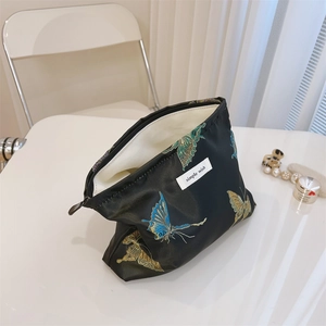 Detail of butterfly jacquard embroidery and metal zipper on the black cosmetic pouch