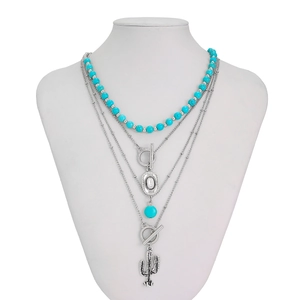 Detail of bohemian layered necklace with turquoise beads and cactus pendant on a bust