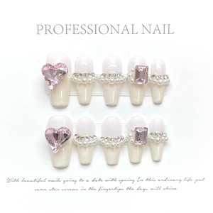 Detailed view of handmade gradient press-on nails with pink heart rhinestones and pearls