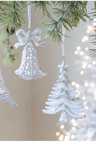Close-up of white flocked Christmas ornaments with silver glitter hanging on tree branches