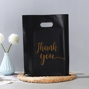 Detail of premium black plastic shopping bag with golden Thank You text on woven mat