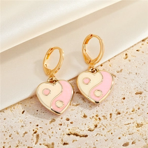 Close-up of heart-shaped Yin Yang hoop earrings in pink and white enamel finish