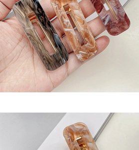 Detail of three rectangular acrylic hair clips in marble textures and brown tones