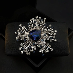 Detailed close-up of a silver brooch with a deep blue triangle crystal and clear rhinestones