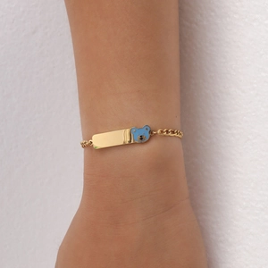 Detail of gold stainless steel bracelet featuring a blue enamel bear and polished rectangle plate