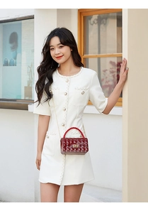 Detail of red quilted PVC crossbody bag paired with a white tweed mini dress