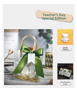 Detail of frosted gift bag with green satin ribbon, bear towel, and handmade flower soap