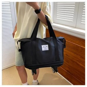 Detail of black travel bag with swivel wheels and dual handles shown in a lifestyle setting