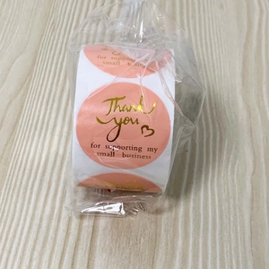 Close-up of pink round thank you stickers with gold foil text for small business packaging