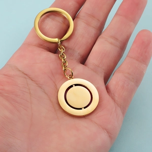 Close-up of a rotating round gold-plated stainless steel pendant keychain held by hand