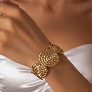 Vue détaillée d'un bracelet manchette doré en spirale avec texture de corde sur le poignet
