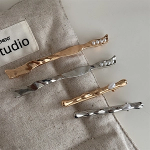 Detailed view of metal hairpins in gold and silver with pearl accents on linen background