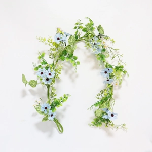 Detailed view of artificial light blue daisy vine with lush green leaves on white background