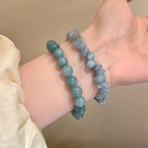 Detail of layered aquamarine camellia beaded bracelets with round and irregular stones