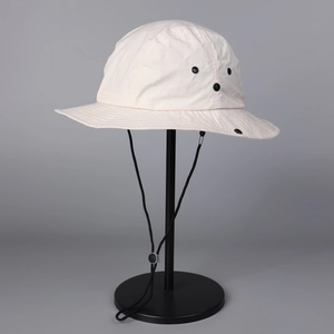 Detail of off-white quick-dry sun hat with adjustable drawstring and metal air vents