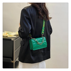 Detail of green quilted crossbody bag with decorative chain and jacquard strap