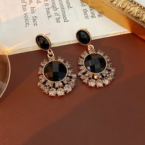 Détail de boucles d'oreilles vintage fleurs avec pierre noire et cristaux brillants