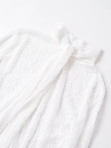 Close-up of white lace blouse featuring delicate floral patterns and ruffled collar texture