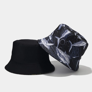 Detail view of reversible bucket hats in black and cartoon shark pattern print