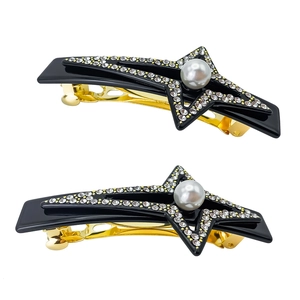 Detalle de dos pinzas de estrella con cristales y perlas blancas sobre metal oro y negro