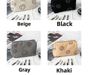 Close-up of corduroy makeup bags in four colors with embroidered smiley face designs